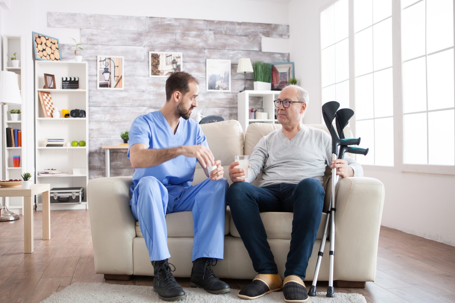 young-male-nurse-in-nursing-home-with-pills-for-senior-man